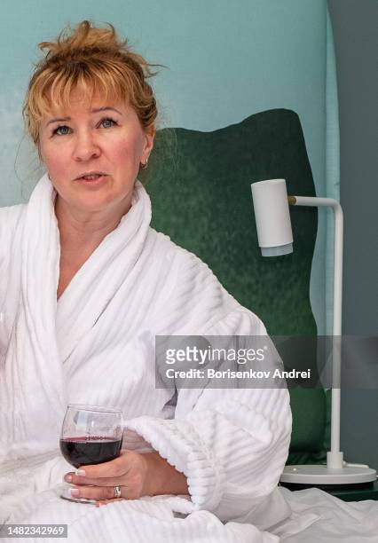 a young woman in a dressing gown and holding a glass of red wine. - lebanon wine stock pictures, royalty-free photos & images