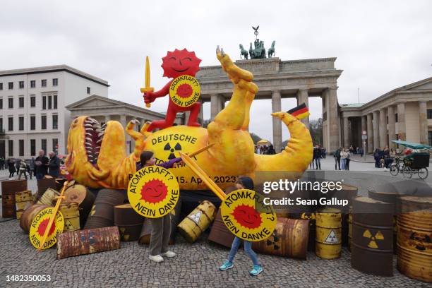 Children pose for their father with swords and shields in front of a Greenpeace installation of a defeated nuclear power dinosaur in front of the...