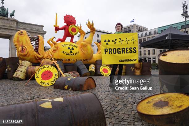 Greenpeace activist stands in front of an installation of a defeated nuclear power dinosaur in front of the Brandenburg Gate to celebrate the...