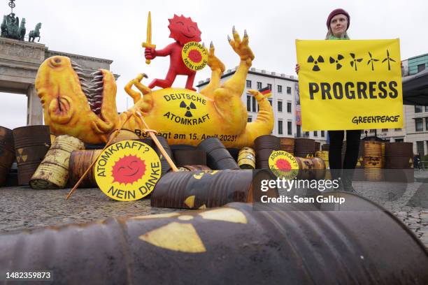 Greenpeace activist stands in front of an installation of a defeated nuclear power dinosaur in front of the Brandenburg Gate to celebrate the...