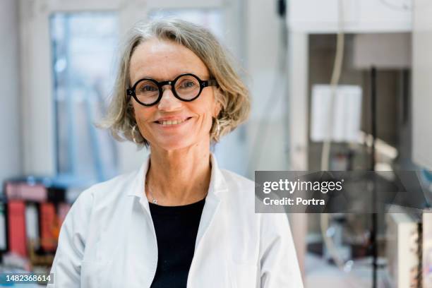 close-up portrait of confident mature female in lab coat working at chemist lab - old laboratory stock pictures, royalty-free photos & images