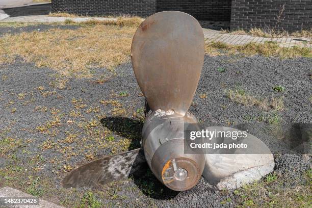 a ship's propeller lies outside on a gravel field as a work of art - ship propeller stock pictures, royalty-free photos & images