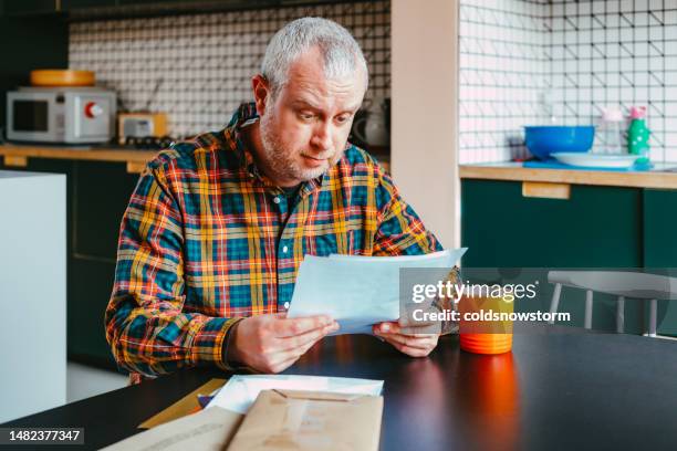 worried man checking bills at home - financial anxiety stock pictures, royalty-free photos & images