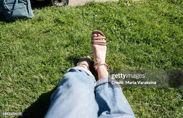 close up of female legs wearing sandals and jeans on green grass - feet selfie woman stockfoto's en -beelden