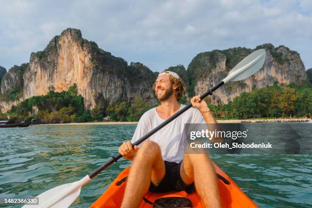 fröhlicher mann seekajak in der nähe des idyllischen railey strandes in krabi - phuket beach stock-fotos und bilder