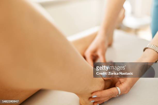 mujer joven en un programa de fisioterapia para el dolor en el pie - pressure point fotografías e imágenes de stock