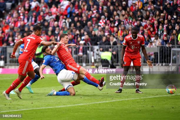 Benjamin Pavard of FC Bayern Munich scores the team's first goal whilst under pressure from Ozan Kabak of TSG Hoffenheim during the Bundesliga match...