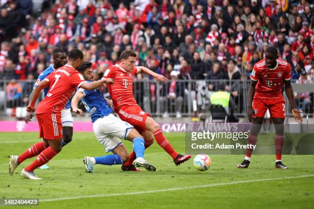Benjamin Pavard of FC Bayern Munich scores the team's first goal whilst under pressure from Ozan Kabak of TSG Hoffenheim during the Bundesliga match...