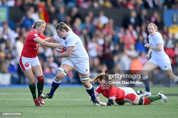 Sarah Beckett of England is tackled by Hannah Jones and Kelsey Jones of Wales during the TikTok Women's Six Nations match between Wales and England...