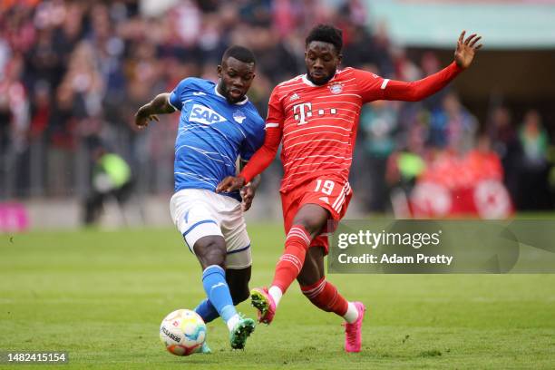 Ihlas Bebou of TSG Hoffenheim and Alphonso Davies of FC Bayern Munich battle for the ball during the Bundesliga match between FC Bayern München and...