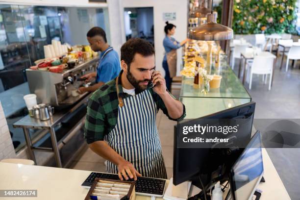 waiter taking a delivery order on the phone at a coffee shop - busy restaurant stock pictures, royalty-free photos & images
