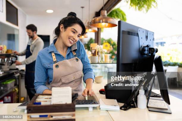 happy waitress taking a delivery order on the phone at a coffee shop - small business stock pictures, royalty-free photos & images