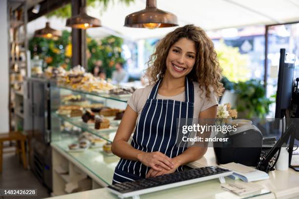 camarera feliz trabajando en el cajero en una cafetería - cafe owner fotografías e imágenes de stock