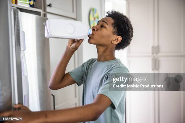 teenage boy drinking milk from carton in kitchen - boy drinking milk stock pictures, royalty-free photos & images