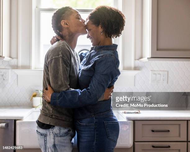 lesbian couple embracing in kitchen - lgbtq  and female domestic life fotografías e imágenes de stock