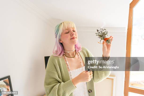 young woman burns sage to remove negative energy - smudging ceremony stock pictures, royalty-free photos & images