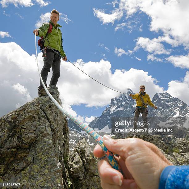 climbers on ridge pull rope tight to teammate - rock climbing stock pictures, royalty-free photos & images