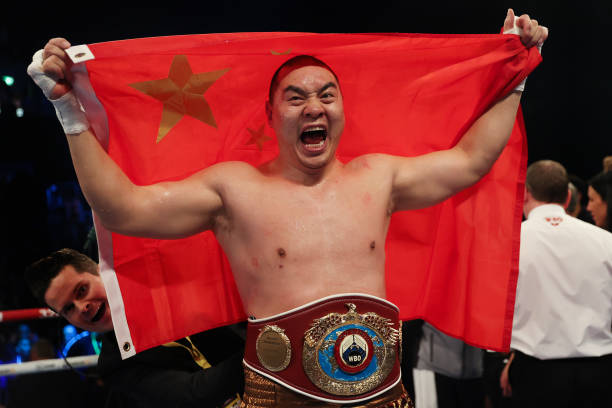 Zhilei Zhang celebrates victory while holding the Chinese flag and wearing the WBO Interim World Heavyweight belt following the WBO Interim World...