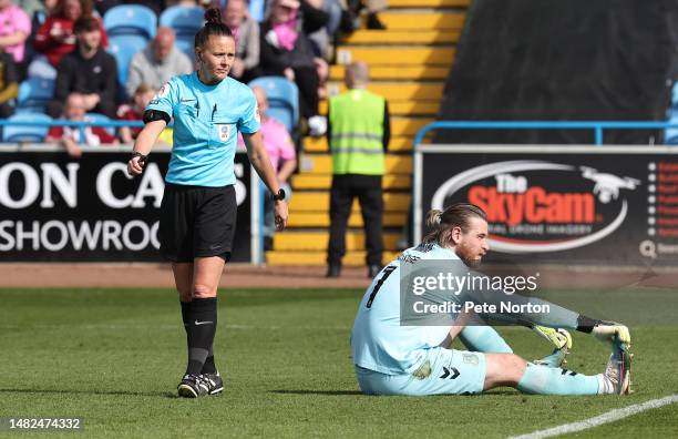 Lee Burge of Northampton Town awaits treatment as referee Rebecca Welch looks on during the Sky Bet League Two between Carlisle United and...