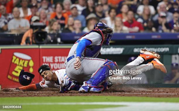 Jeremy Pena of the Houston Astros scores on a sacrifice fly as Jonah Heim of the Texas Rangers is late on the tag in the fourth inning of the game at...