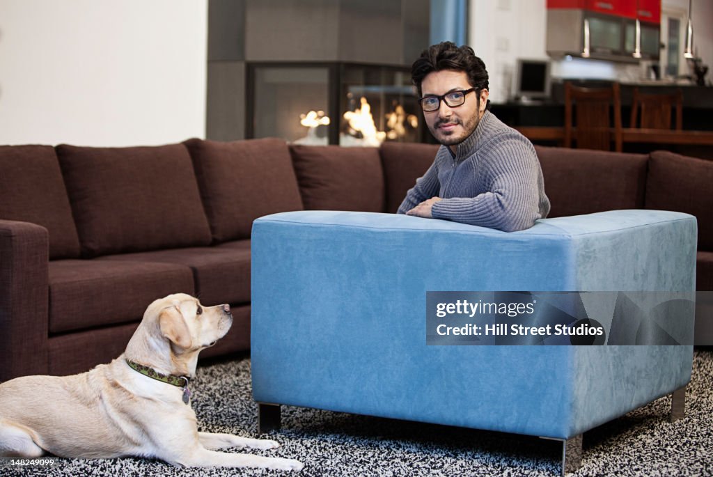 Hispanic man sitting in living room with dog