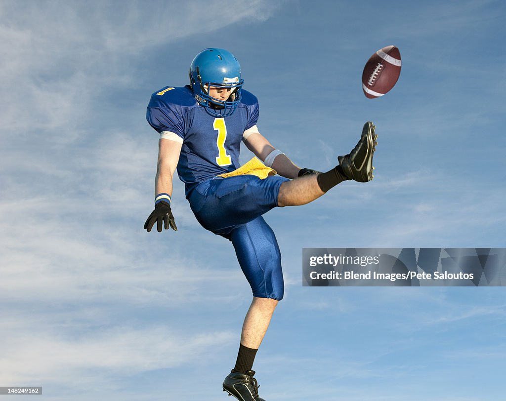 Caucasian football player kicking football