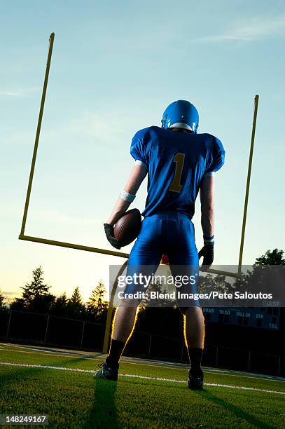 caucasian football player standing with football - american football player back stock pictures, royalty-free photos & images