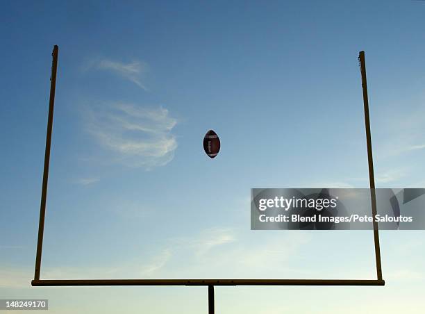 football being thrown through goal posts - american football goal posts stock pictures, royalty-free photos & images