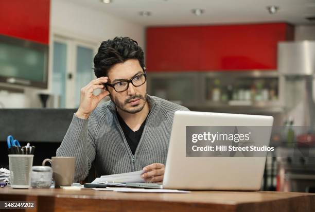 hispanic man paying bills on computer - concerned laptop stock pictures, royalty-free photos & images