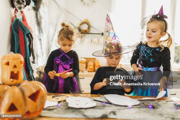 baby girls crafting scary face masks for halloween. coloring and glue class for children - halloween craft stock pictures, royalty-free photos & images