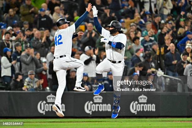 Eugenio Suarez of the Seattle Mariners celebrates with third base coach Manny Acta after hitting a solo home run during the fourth inning against the...