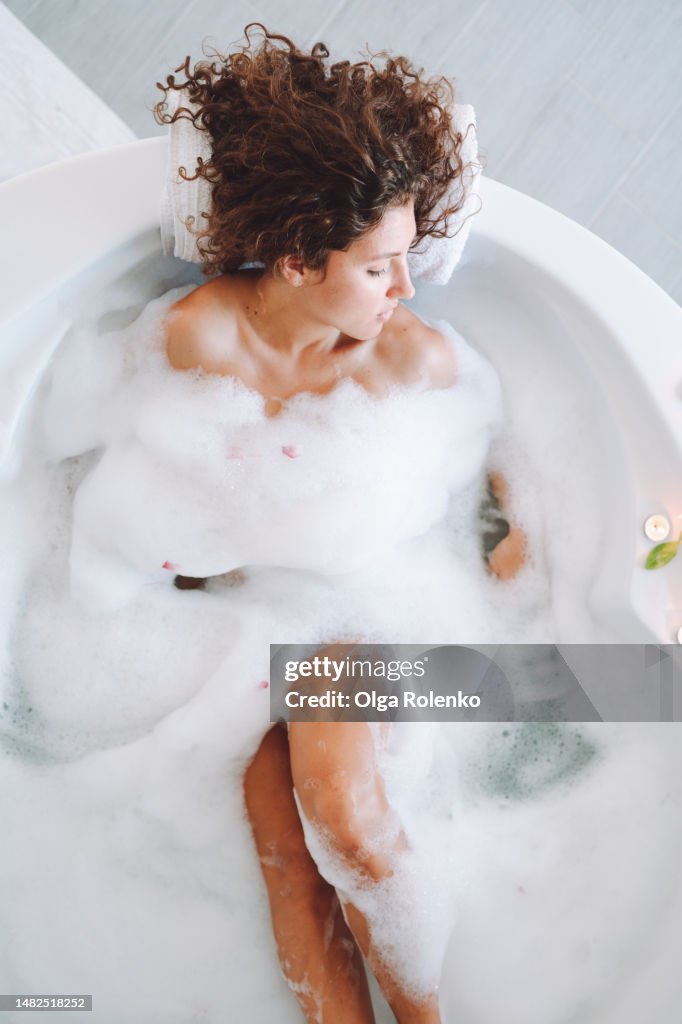 Woman in bubble foam water. Immerse yourself in pure bliss with spa bath's aromatherapy and healthy bath treatments.