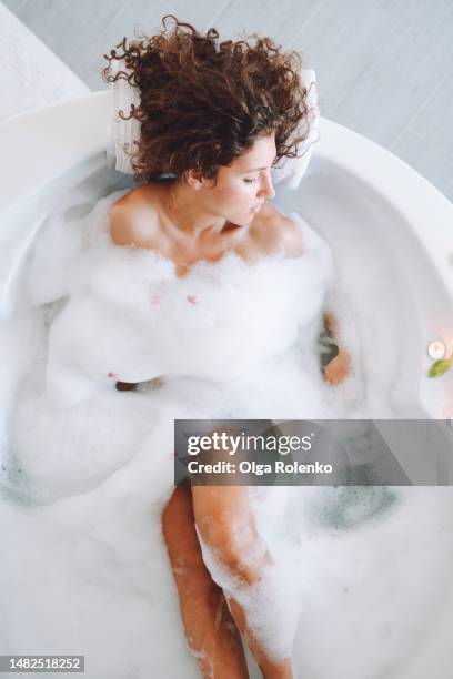 woman in bubble foam water. immerse yourself in pure bliss with spa bath's aromatherapy and healthy bath treatments. - bathhouse stock pictures, royalty-free photos & images