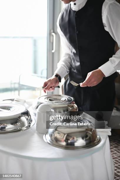 server setting up room service in a hotel room - servicio de habitaciones fotografías e imágenes de stock
