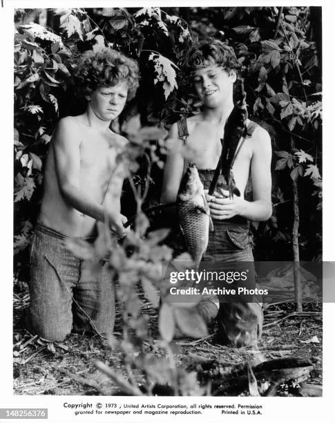 Johnny Whitaker and Jeff East catch fish in a scene from the film 'Tom Sawyer', 1973.