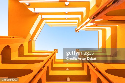 Visual yellow architecture with inner courtyard lightwell from directly below, blue sky and creative perspective.