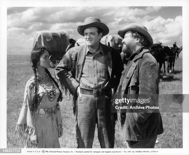 Susan Cabot, Van Heflin, and Jack Oakie talking out in the prairie in a scene from the film 'Tomahawk', 1951.