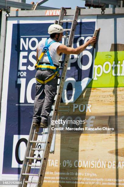 worker fixing advertising billboard - billboard posting stock pictures, royalty-free photos & images