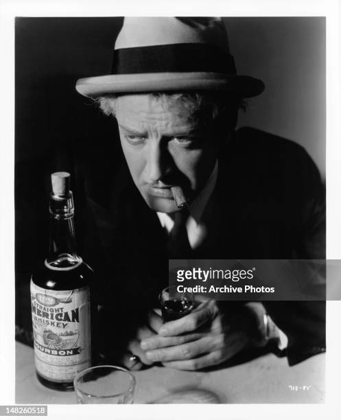 Otto Kruger holding shot glass while puffing on cigar in a scene from the film 'The Women In His Life', 1933.
