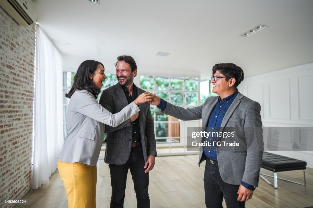 Real estate agent giving new house key to a couple