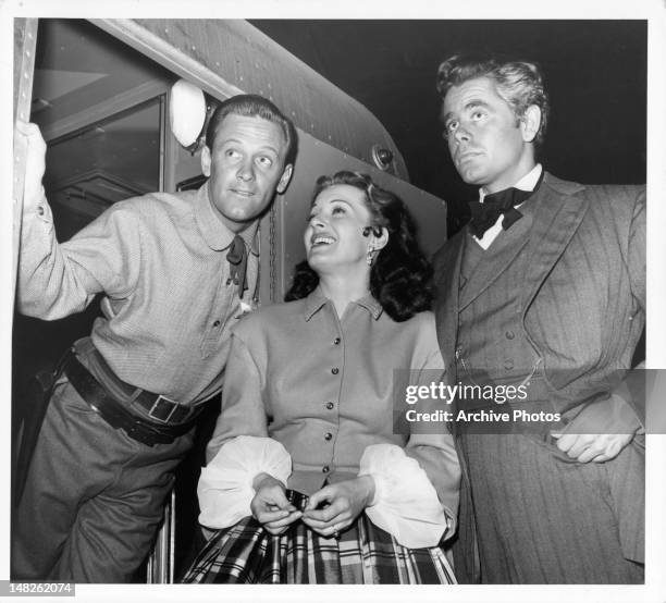 William Holden, Ellen Drew, and Glenn Ford standing outside train in a scene from the film 'The Man From Colorado', 1948.