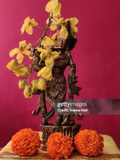brass idol of lord krishna decorated with marigold and amaltas/golden shower flowers/vishu/vishu kani/kerala - amaltas foto e immagini stock
