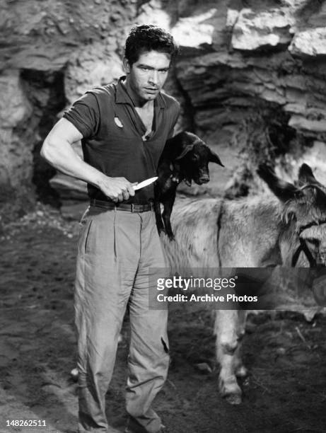 Stephen Boyd holding pig and knife in a scene from the film 'The Night Heaven Fell', 1958.