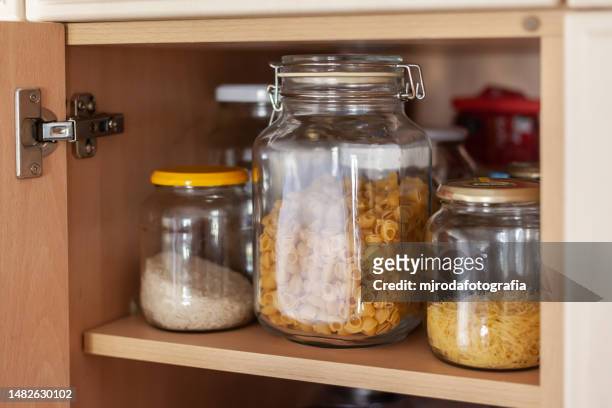 botes de cristal llenos de pasta y arroz en un armario de la despensa - despensa stock pictures, royalty-free photos & images