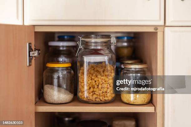 botes de cristal llenos de pasta y arroz en un armario de la despensa - cabinet stock pictures, royalty-free photos & images