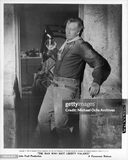 Stumbling John Wayne leaning against wall in a scene from the film 'The Man Who Shot Liberty Valance', 1962.