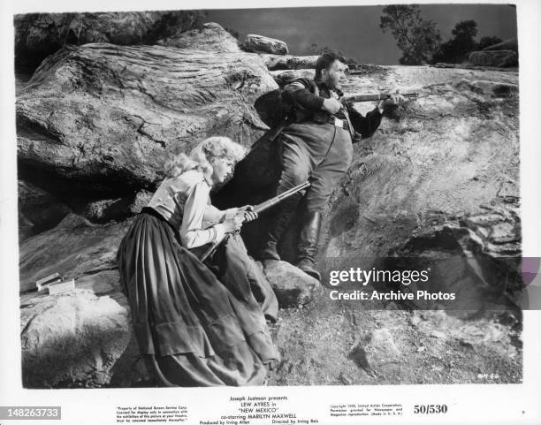 Marilyn Maxwell holding rifle with cavalry man in a scene from the film 'New Mexico', 1951.