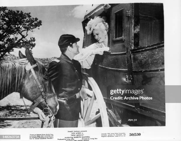 Lew Ayres smiling at Marilyn Maxwell in stagecoach in a scene from the film 'New Mexico', 1951.