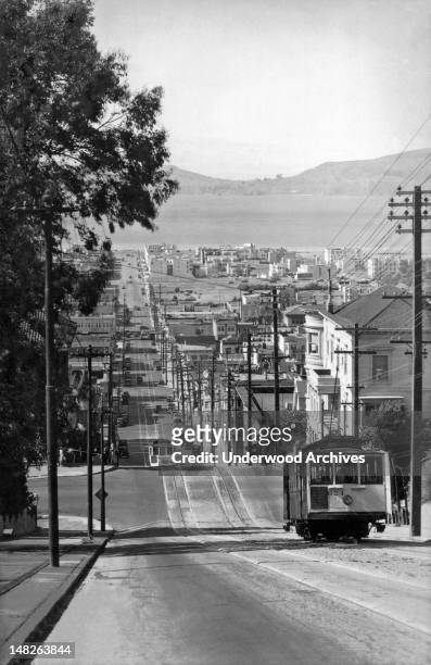 Cable cars on the Fillmore Street hill looking down at the Marina with Angel Island in the background, San Francisco, California, circa 1920.