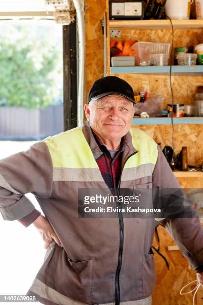 portrait of a 69 year old man in a garage. retired garage worker. - ouïgour photos et images de collection